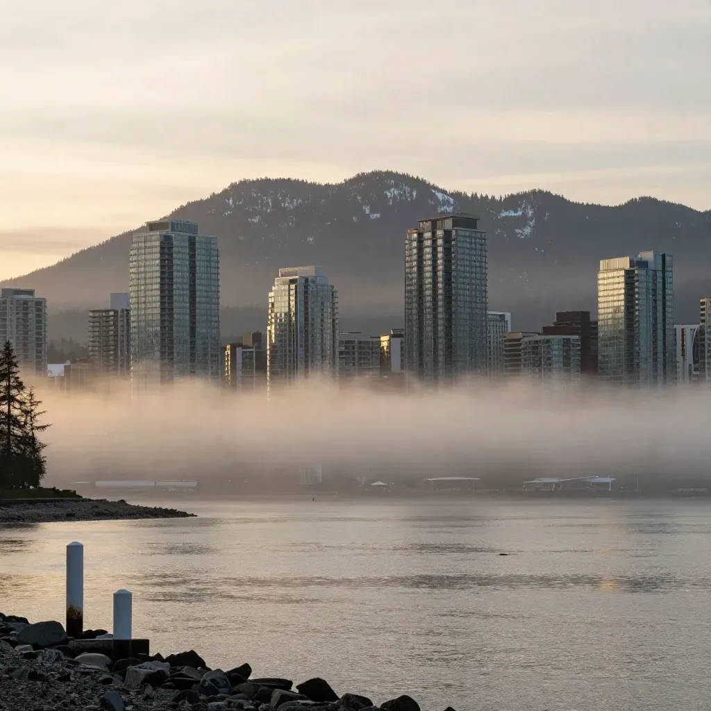 Foggy Vancouver skyline and mountains over calm inlet at dawn